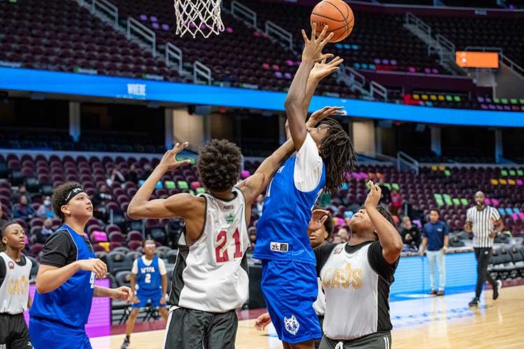 Two young basketball players jump for a ball during a game.