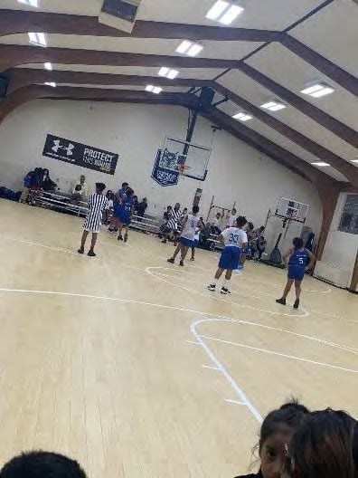 Adults and children playing basketball on a wooden court.