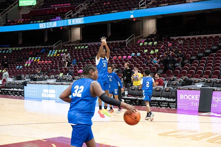 Children in blue jerseys playing basketball in an arena.
