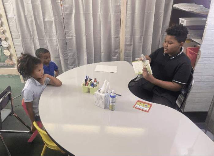 Three children reading together at a table.