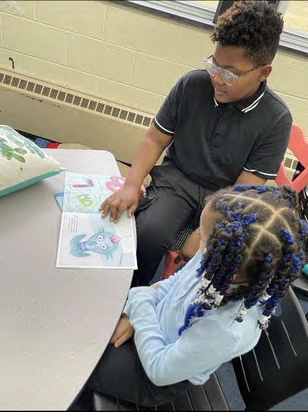 Two children reading a book with colorful illustrations.