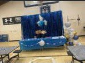 Gymnasium event setup with blue drapes and balloons.