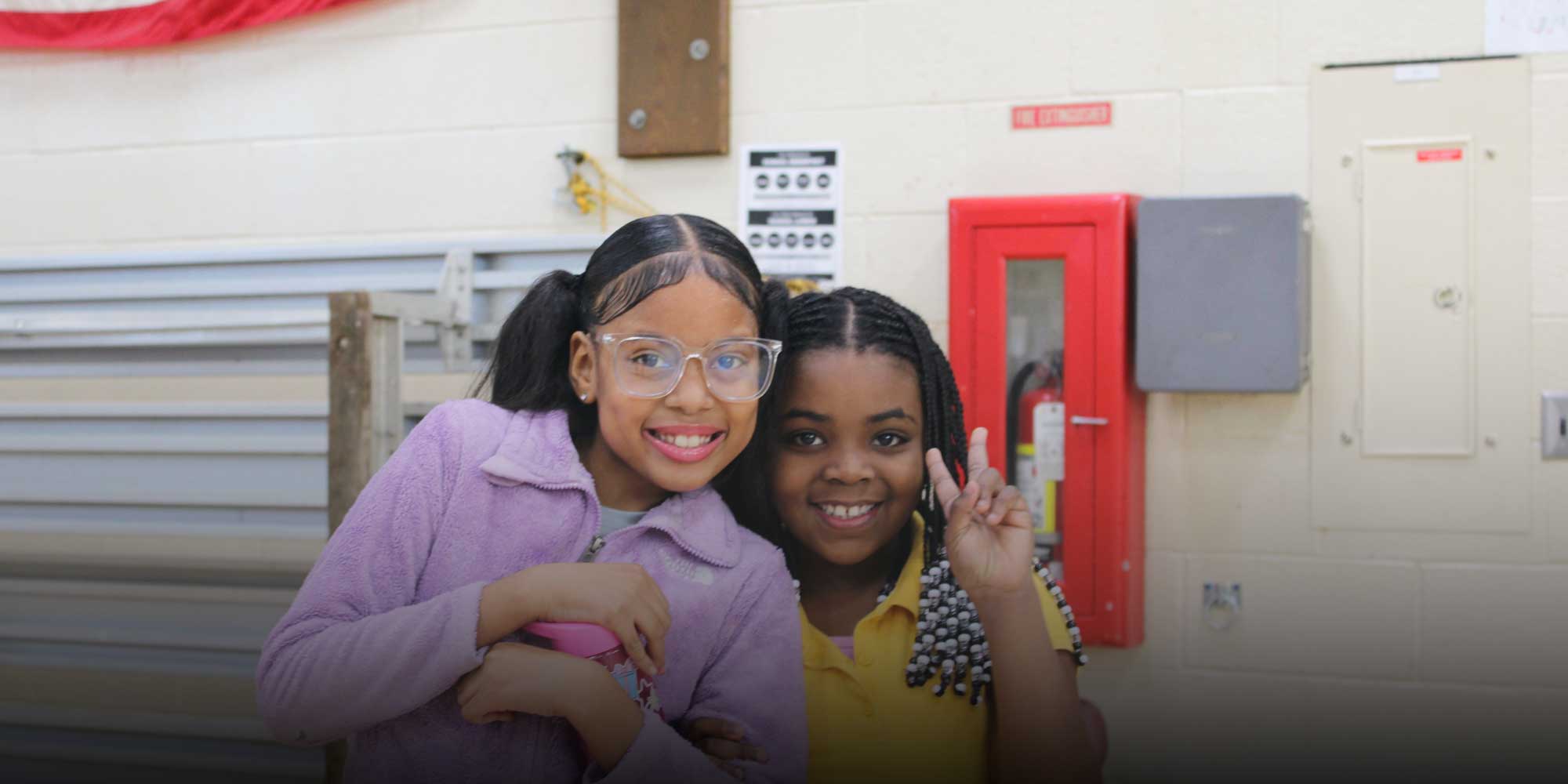 Two smiling students posing together, one making a peace sign.