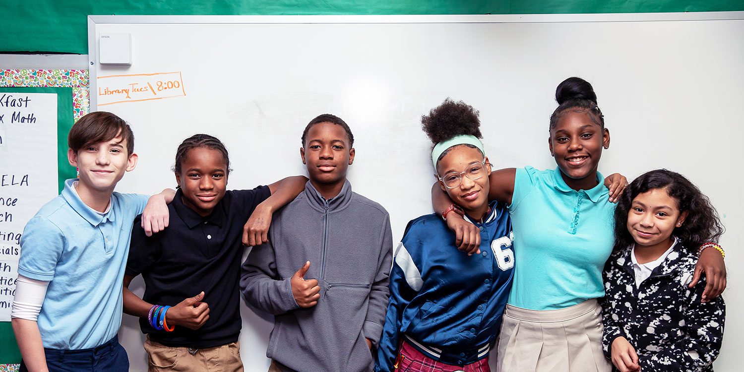 Group of smiling students with their arms around each other