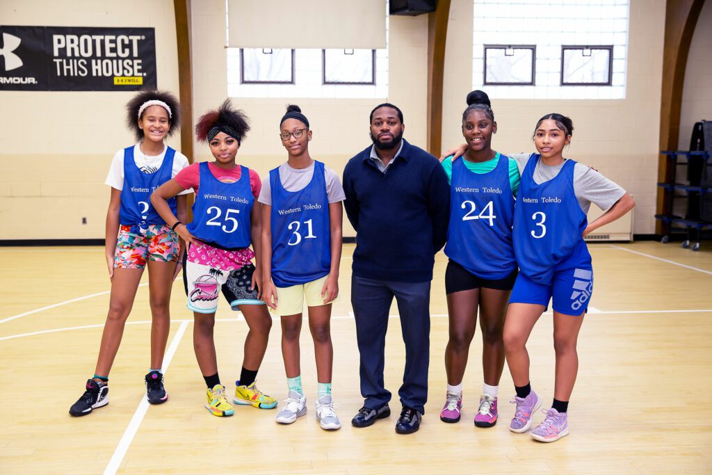 A teacher and a group of students on the basketball court