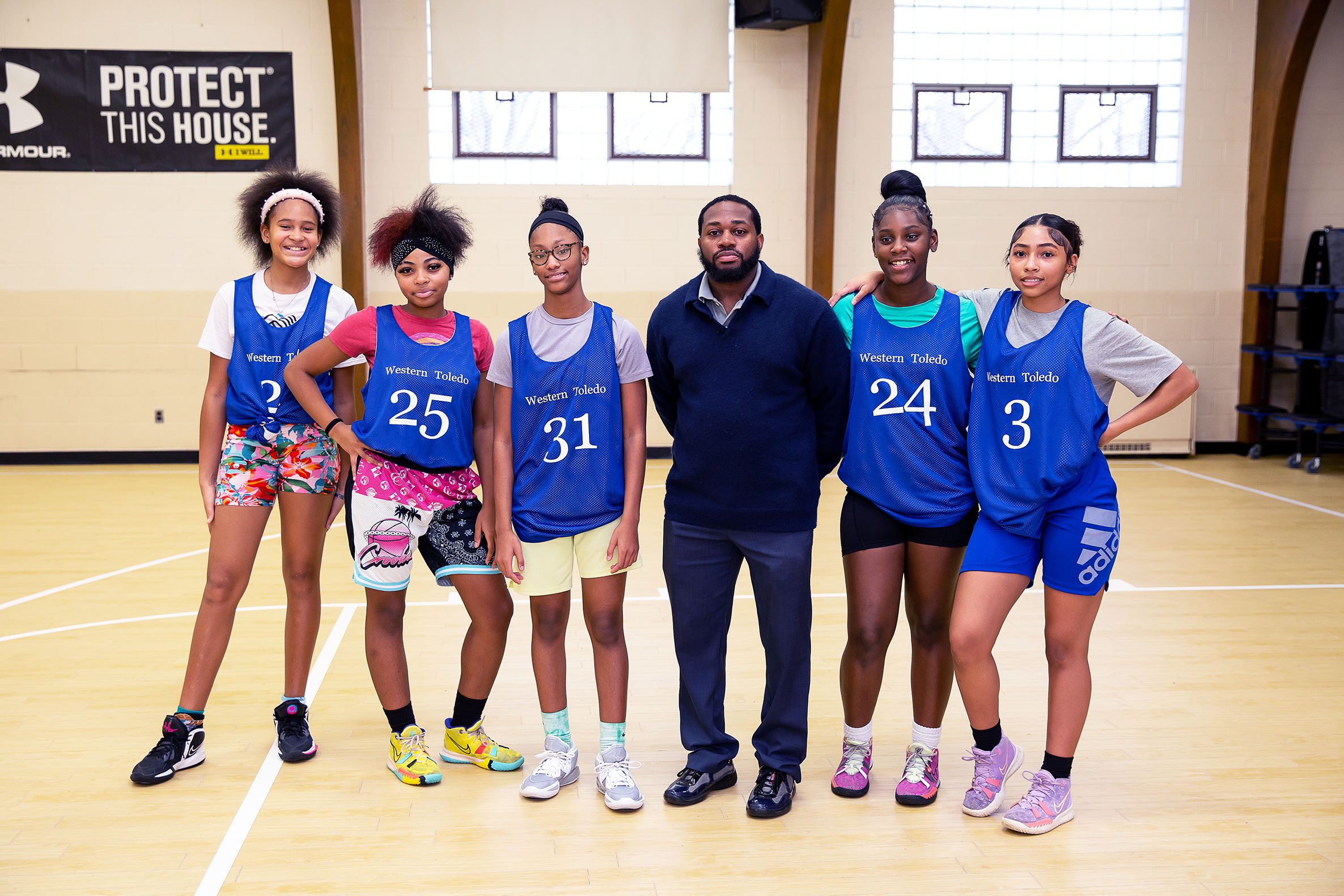 A teacher and a group of students on the basketball court