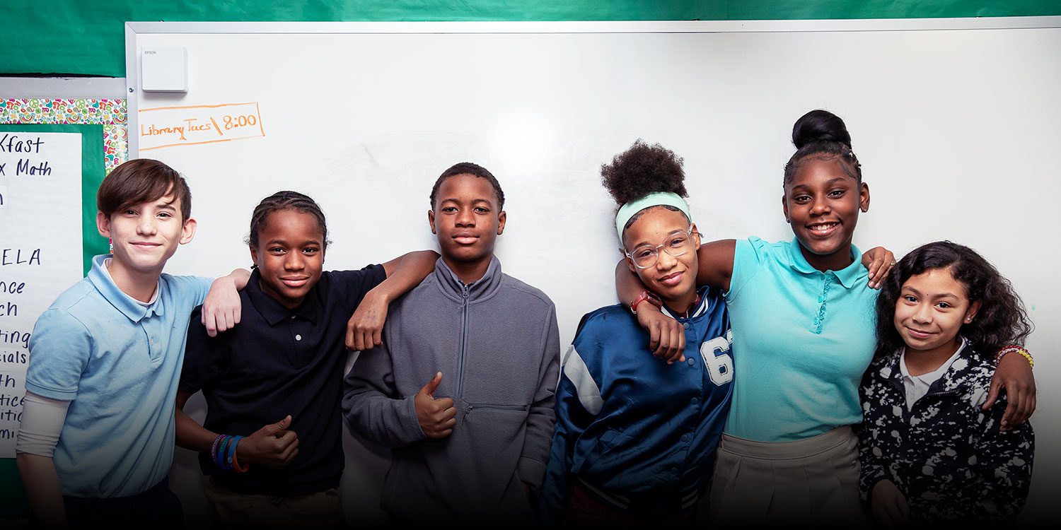 Group of smiling students with their arms around each other